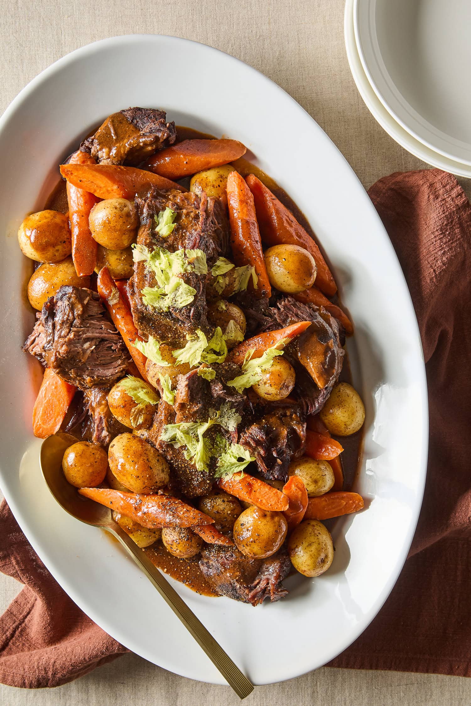A platter with cooked chuck roast and roasted carrots and potatoes.