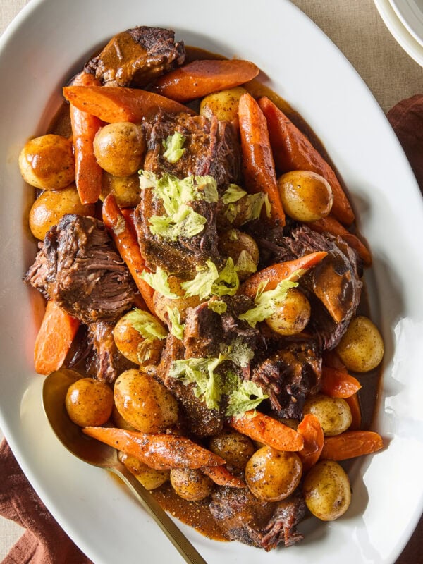 A classic pot roast garnished with parsley rests on a platter.