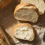 Slices of French bread being topped with butter.