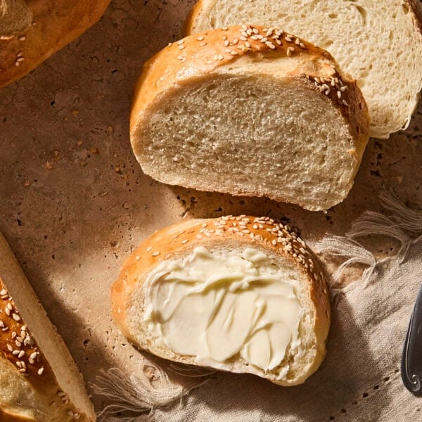 Slices of French bread being topped with butter.