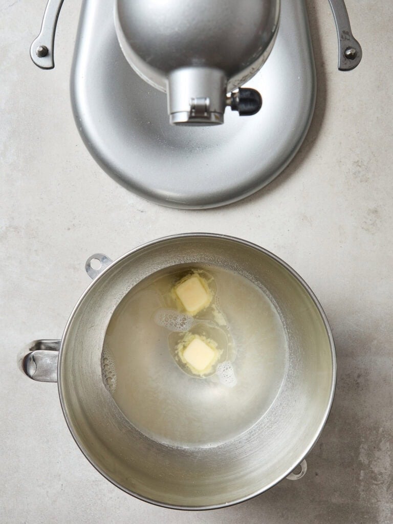 Butter, water, sugar, and salt dissolving in a metal bowl to begin bread-making.