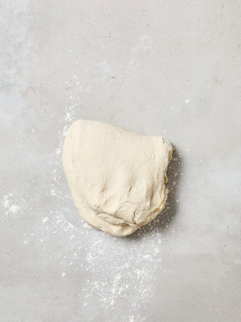 Bread dough after being stretched on a floured surface.