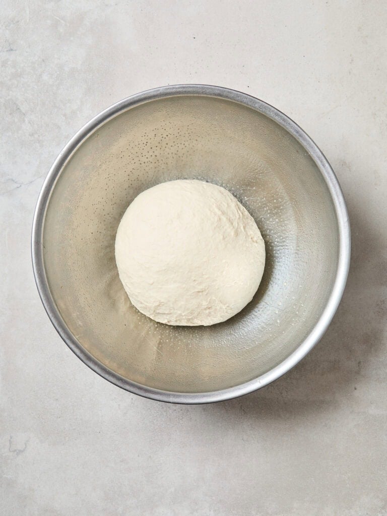 Placing bread dough in an oiled bowl to rise.