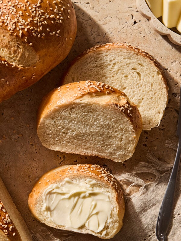 Slices of French bread on a counter topped with butter.