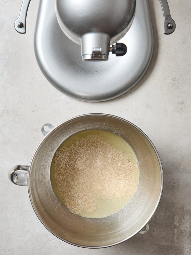 Adding yeast to a metal bowl to make bread.