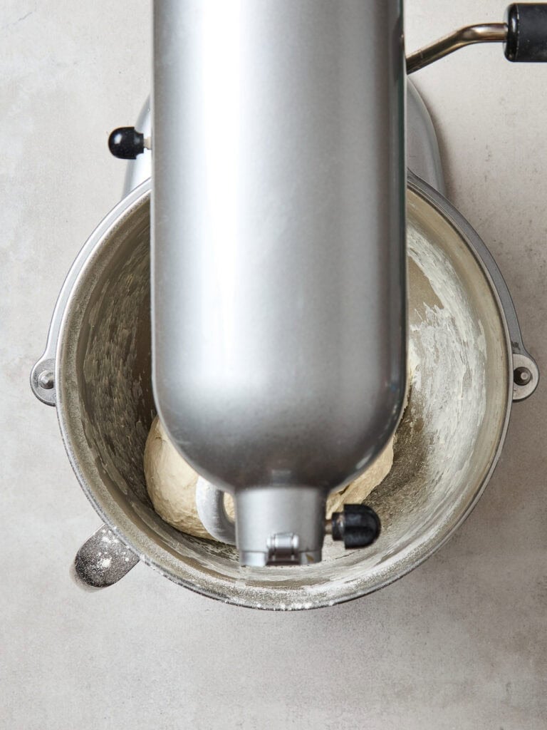 Mixing ingredients with a stand mixer to create French bread.