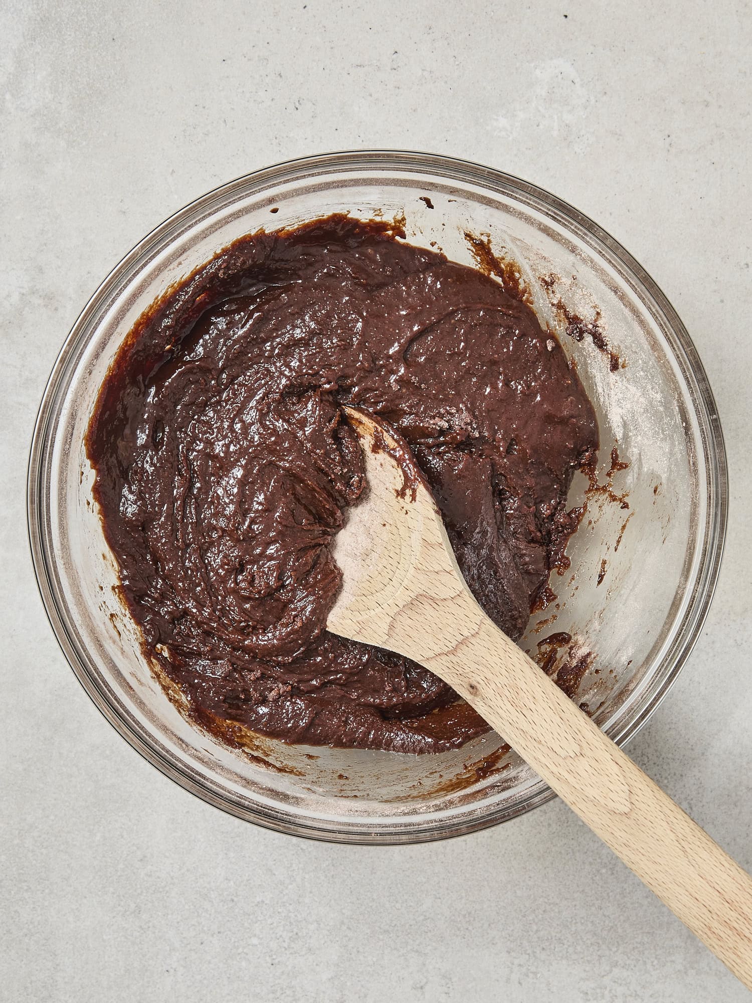 Glass bowl with dry and wet chocolate ingredients mixed together.