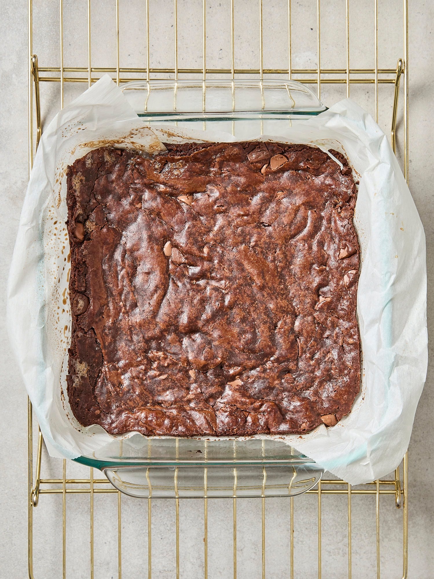 Baked fudgy brownies cooling on a baking rack in the pan.