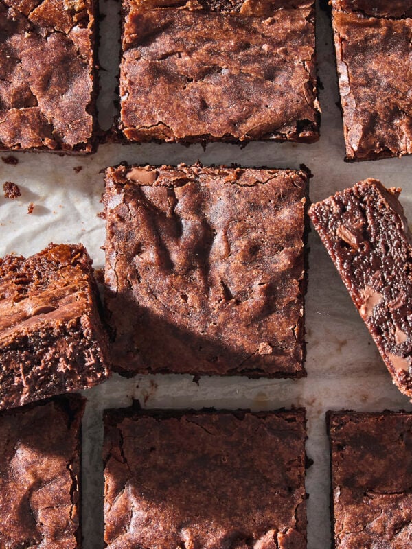 Fudgy brownies cut into individual squares with some turned on their sides to show interior.