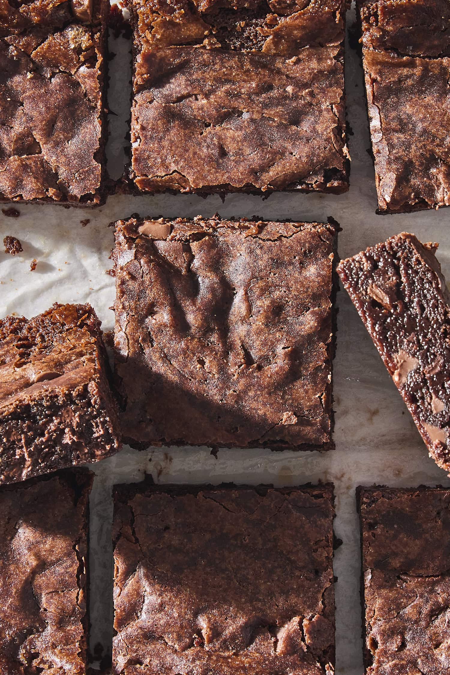Fudgy brownies cut into individual squares with some turned on their sides to show interior.