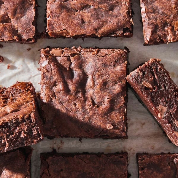 Sliced fudgy brownies sitting on a piece of parchment.