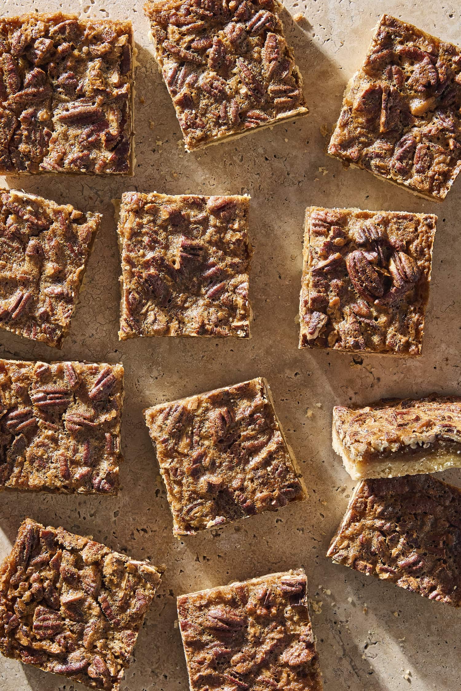 Sliced bars with pecans on top sitting on stone surface.
