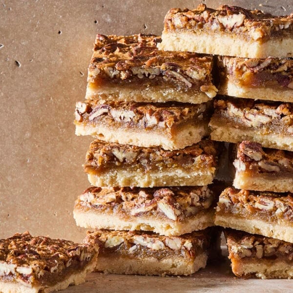 Stacks of pecan pie bars on stone surface.