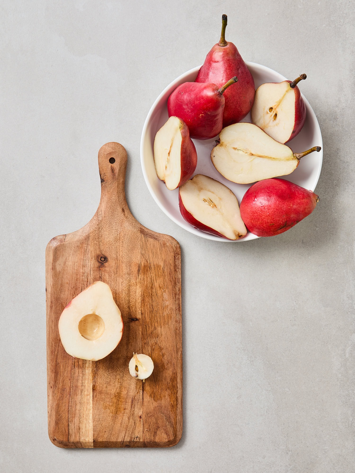 Cutting red pears in half and removing the seeds.
