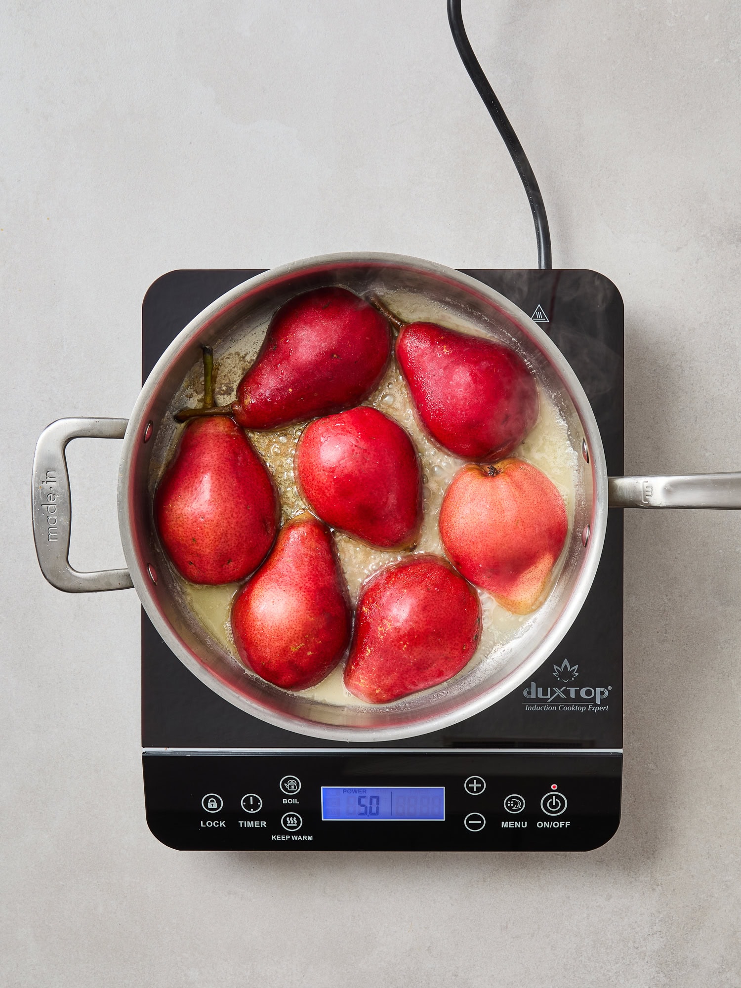 Pear halves cook face down in a pan.