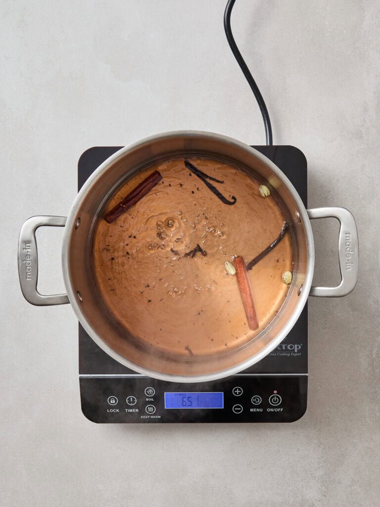 Poaching liquid for poached pears simmers in a saucepan.