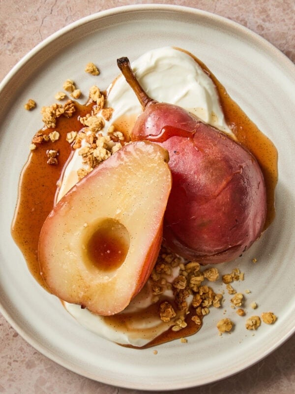 Poached pears on a plate with Greek yogurt and granola.
