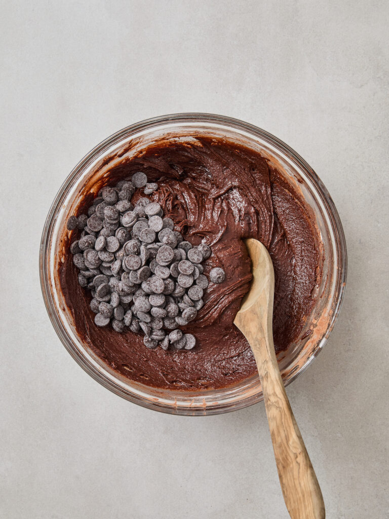 Chocolate chips being added to a bowl with chocolate brownie batter.