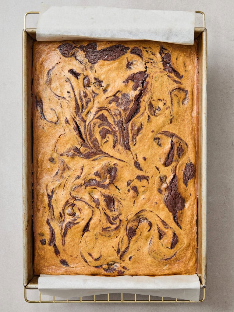 A pan of pumpkin cheesecake brownies cools after baking.