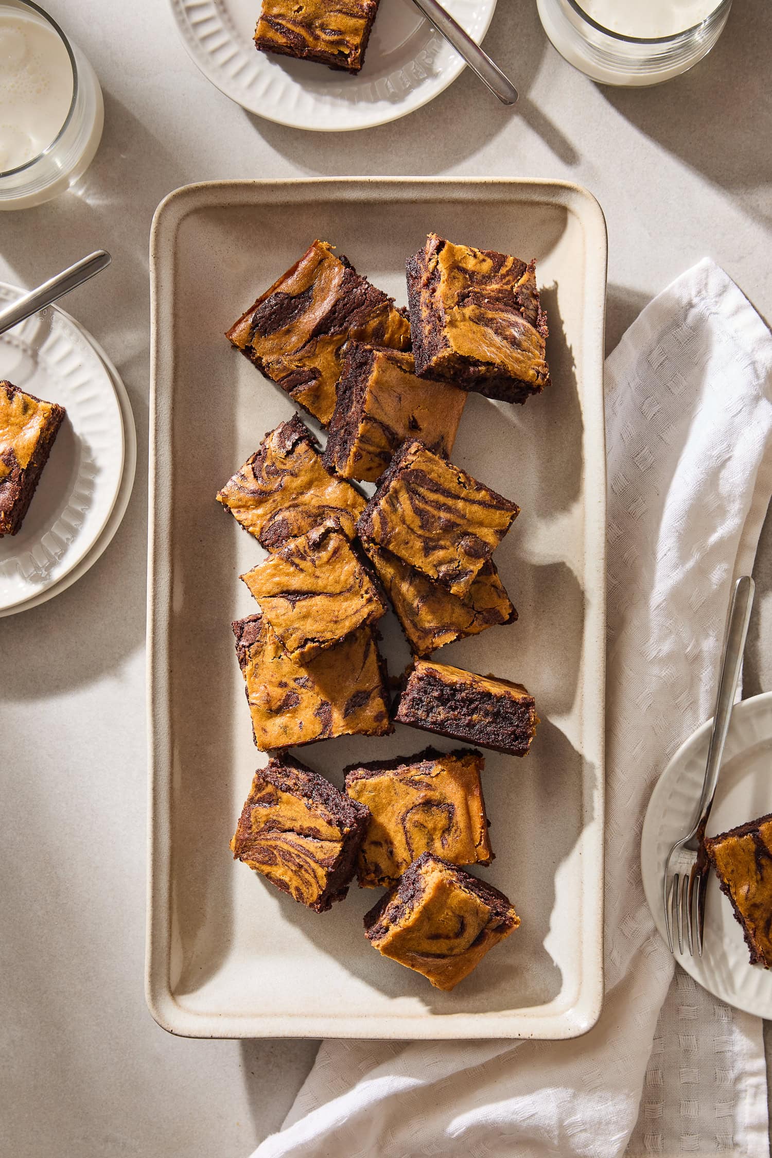 Pumpkin cheesecake brownies scattered across a serving platter.