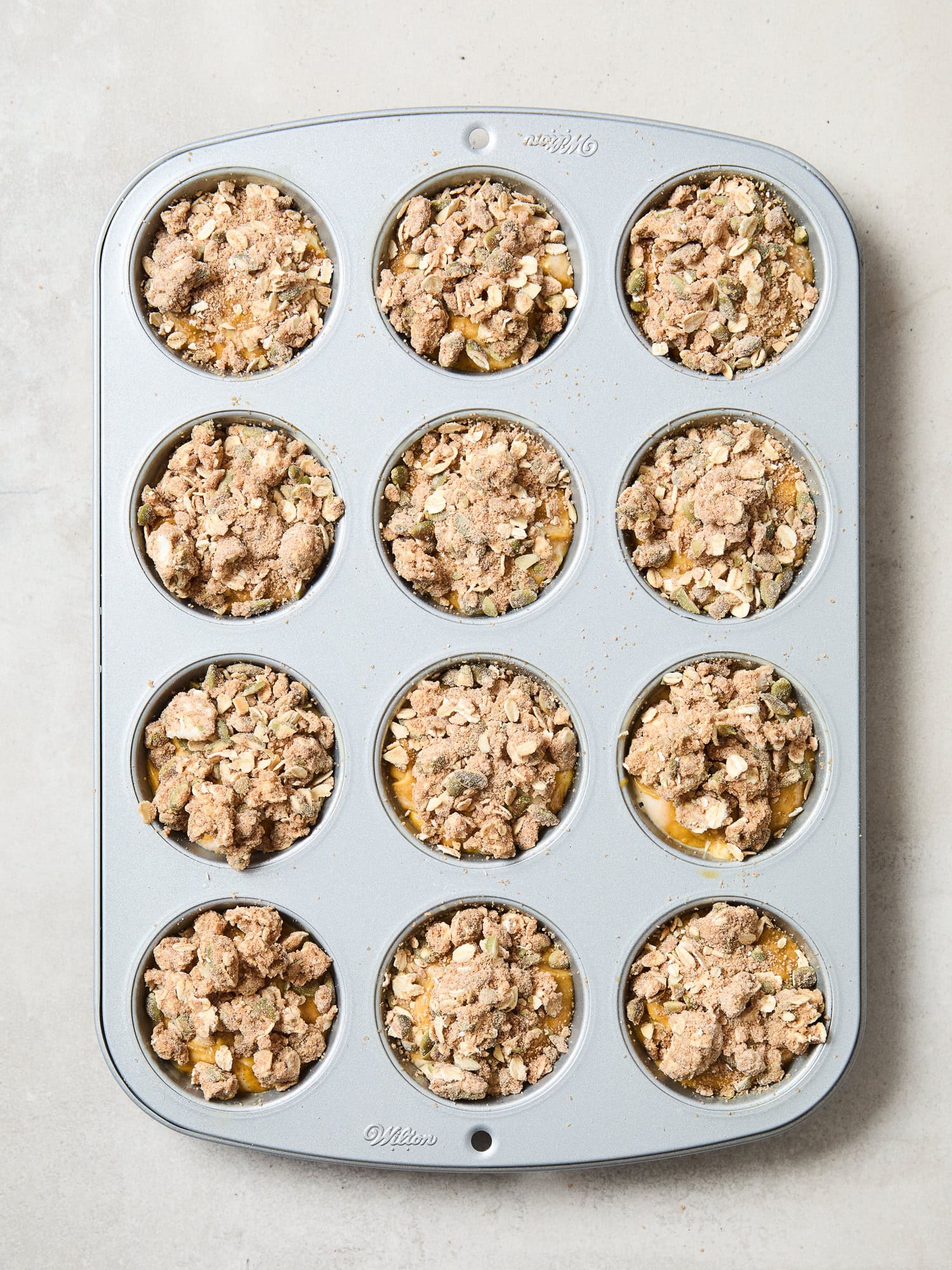 Pumpkin cheesecake muffin batter topped with streusel prior to baking.