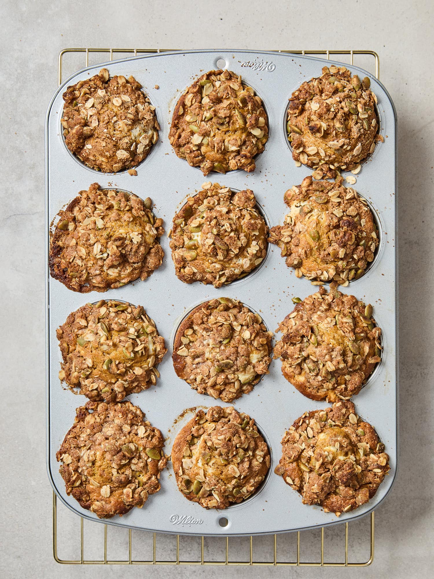 Pumpkin cheesecake muffins cooling on a rack after baking.