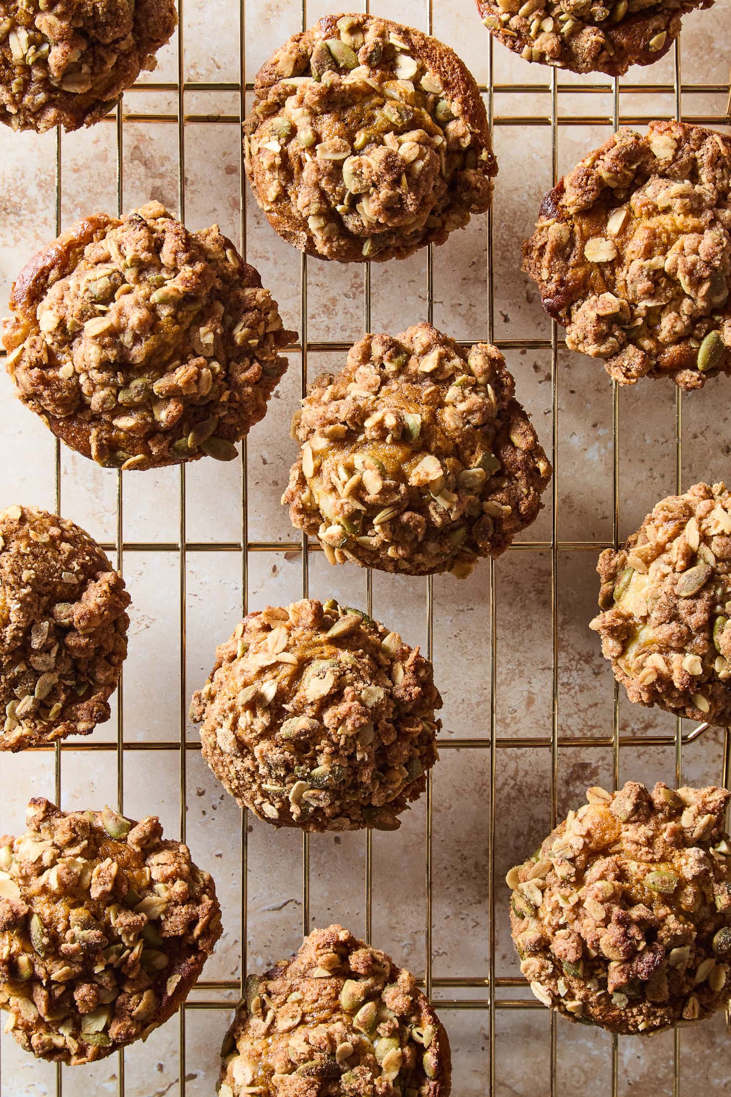 Rolled oat streusel topping over pumpkin cheesecake muffins cooling on a rack.