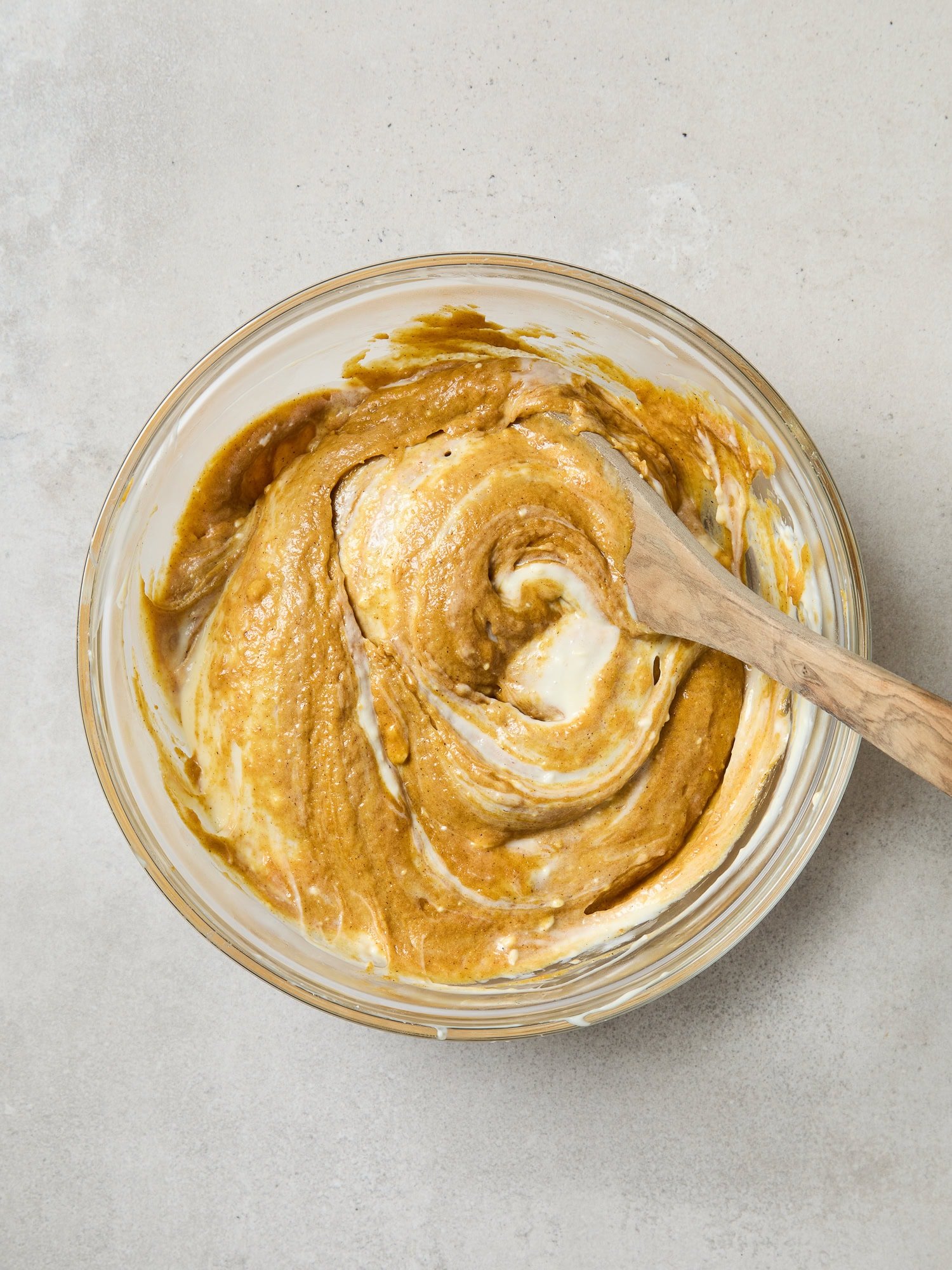 Batter for pumpkin muffins being mixed with cheesecake filling.