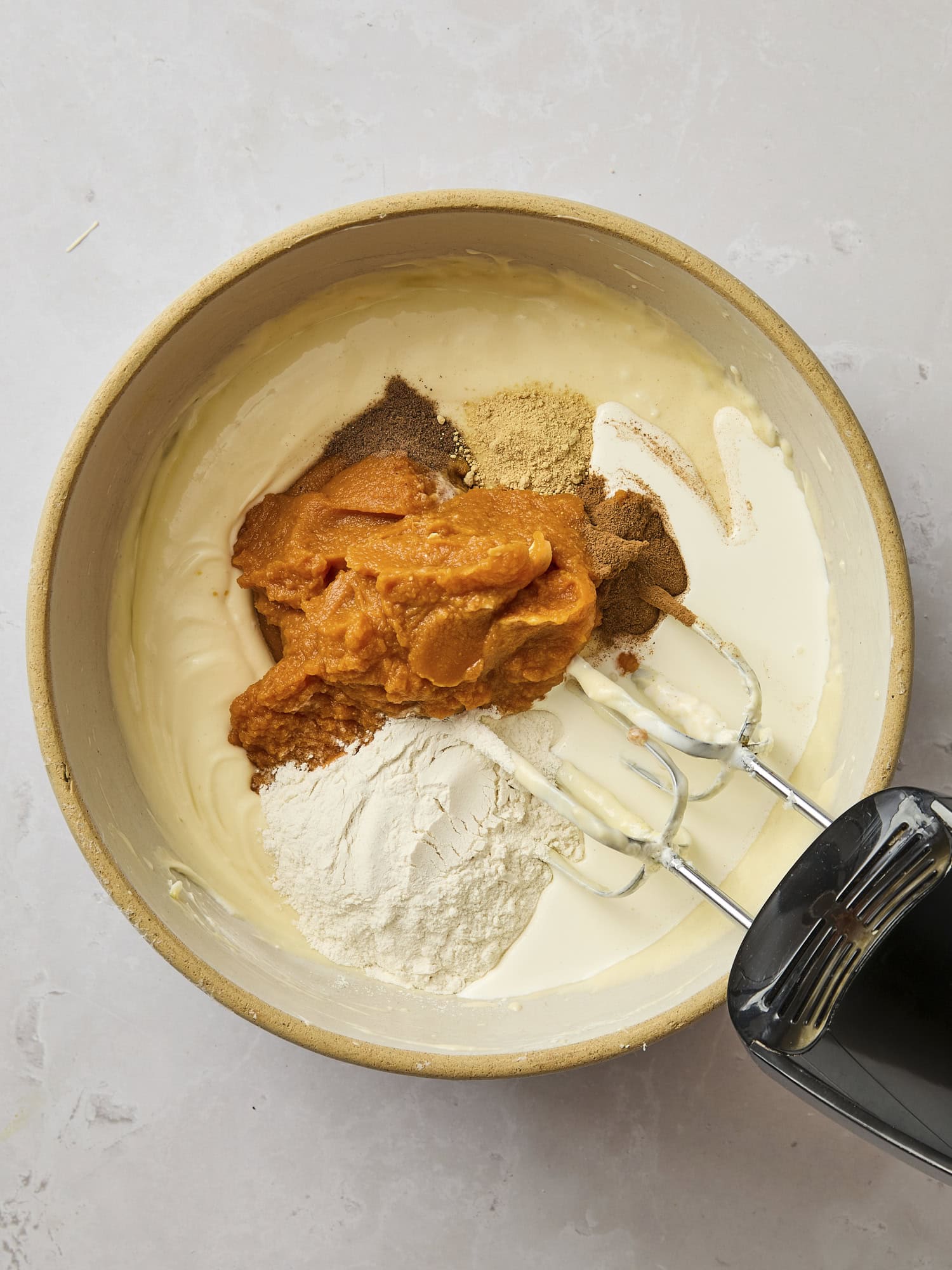 Mixing bowl with pumpkin puree and spices for a pumpkin cheesecake.