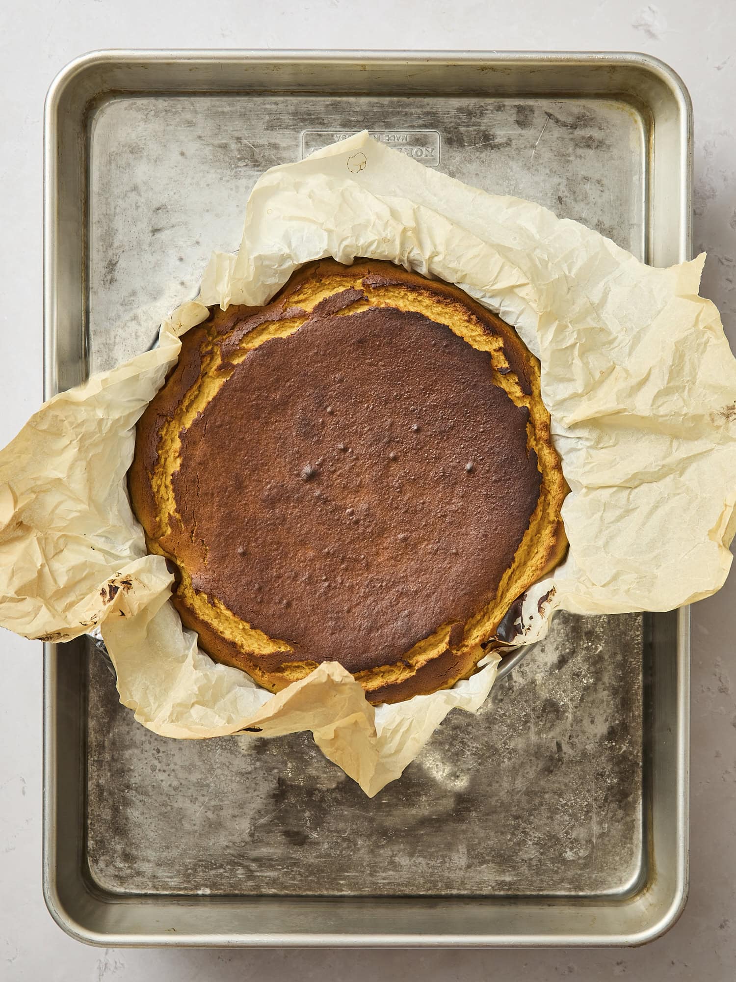 Baked Basque pumpkin cheesecake on baking pan.