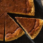 Basque cheesecake with dark top with slices cut out.