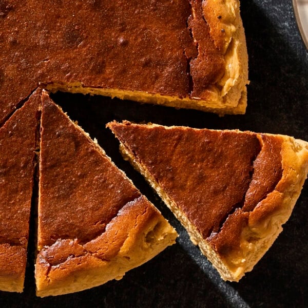 Basque cheesecake with dark top with slices cut out.