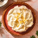 Cranberry tart with orange whipped cream before being sliced.