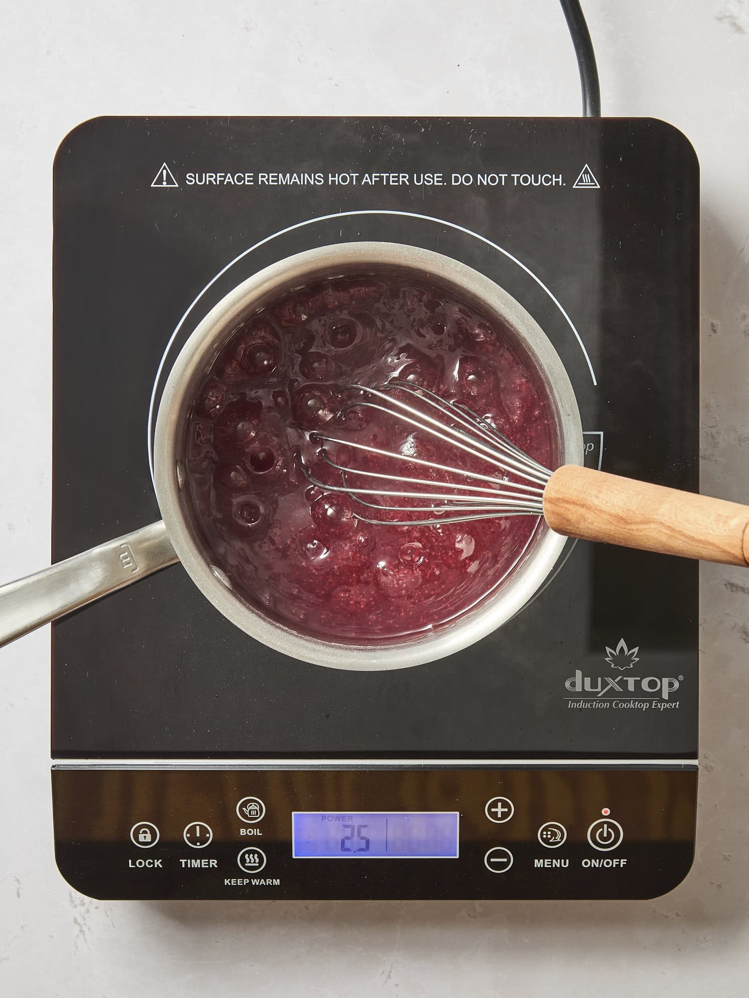 Cooktop with saucepan filled with cranberry juice filling heating.