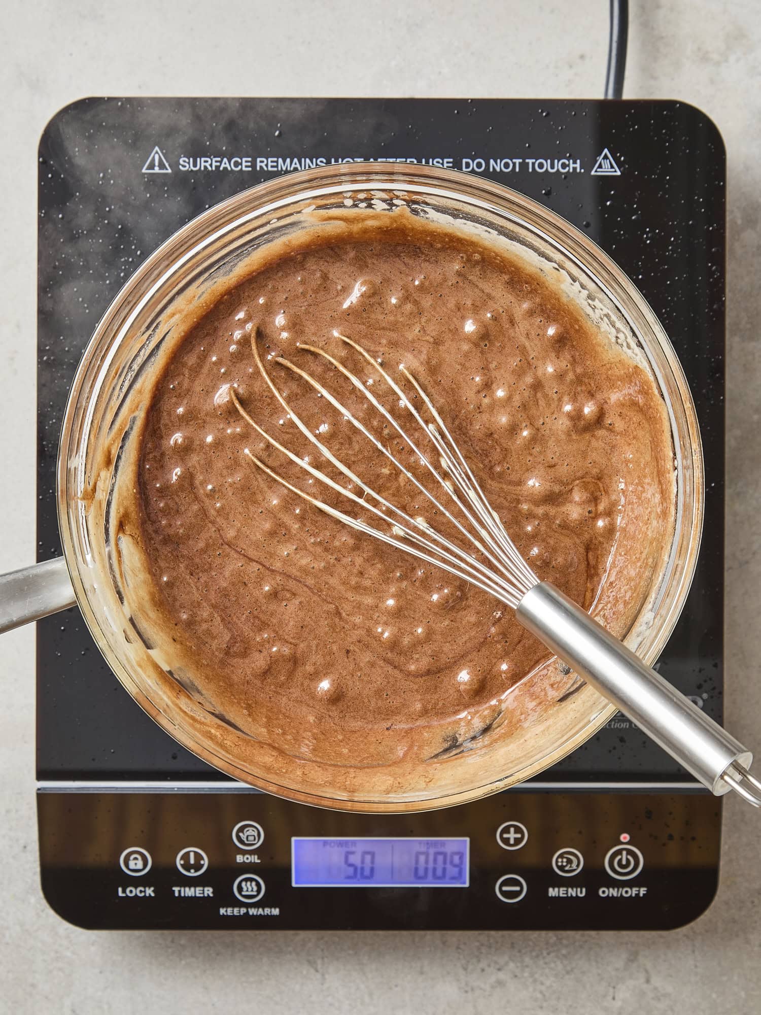 Glass bowl with chocolate and egg mixture cooking for pie filling.