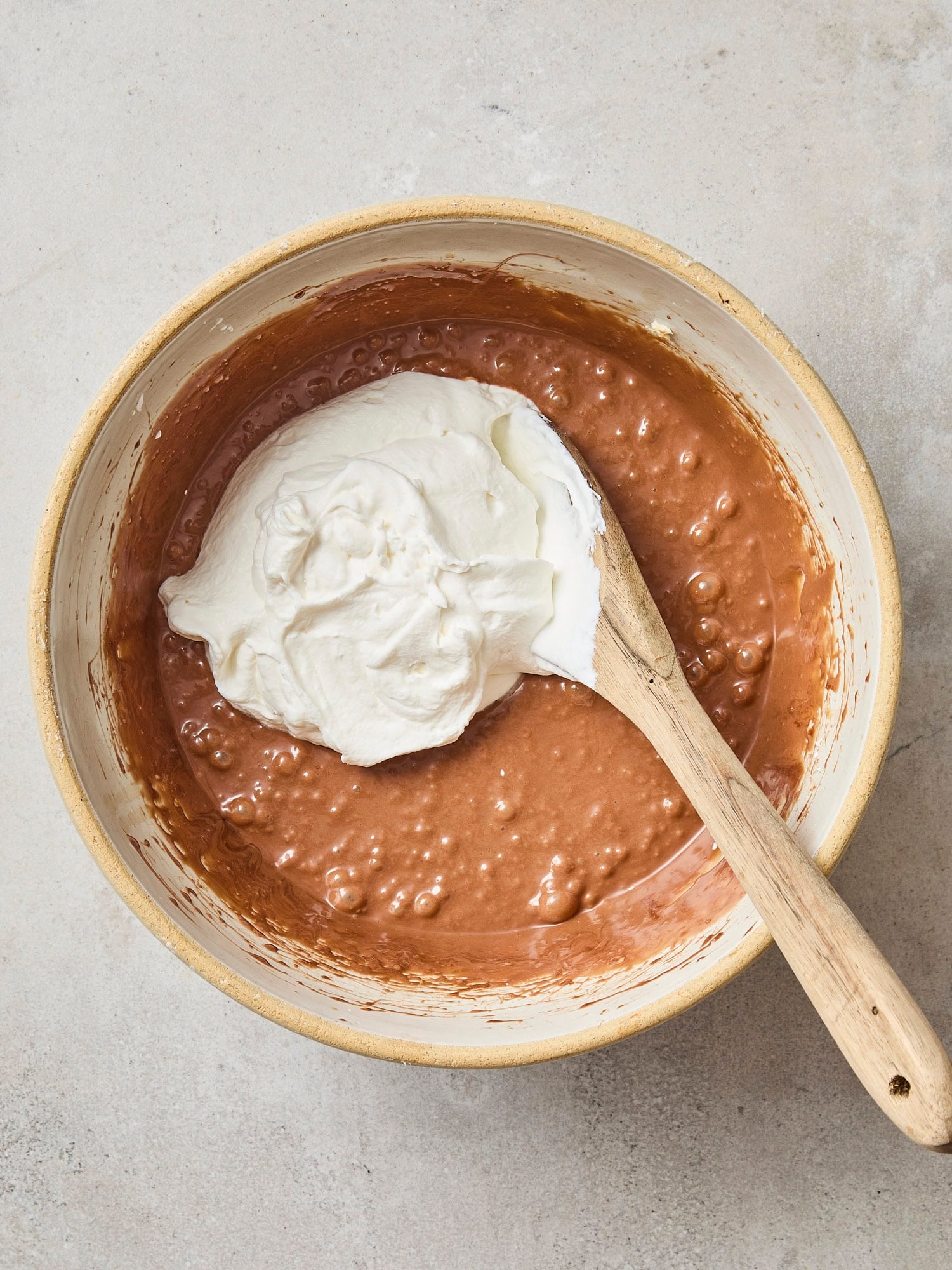 Stone bowl with chocolate mixture with whipped cream about to be mixed together.