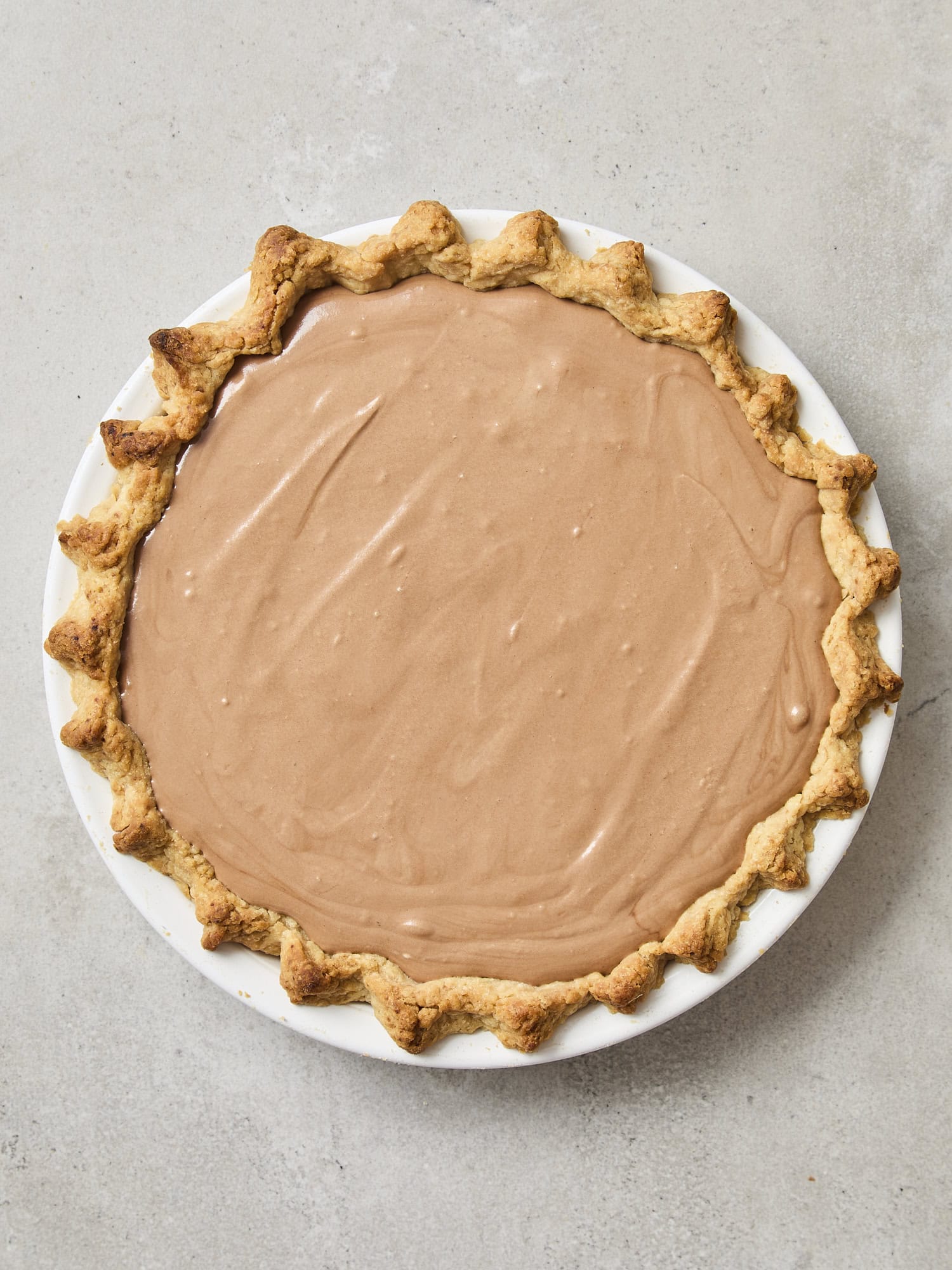Baked pie crust with chocolate filling poured inside.
