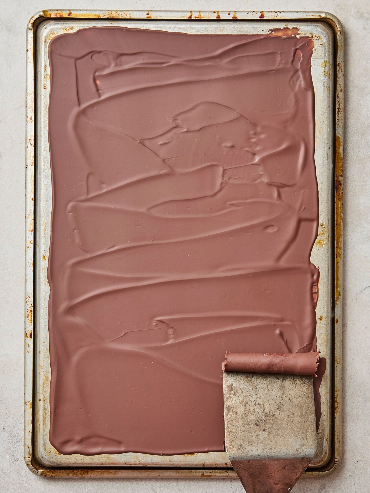 Cooled chocolate with offset spatula forming chocolate curls.