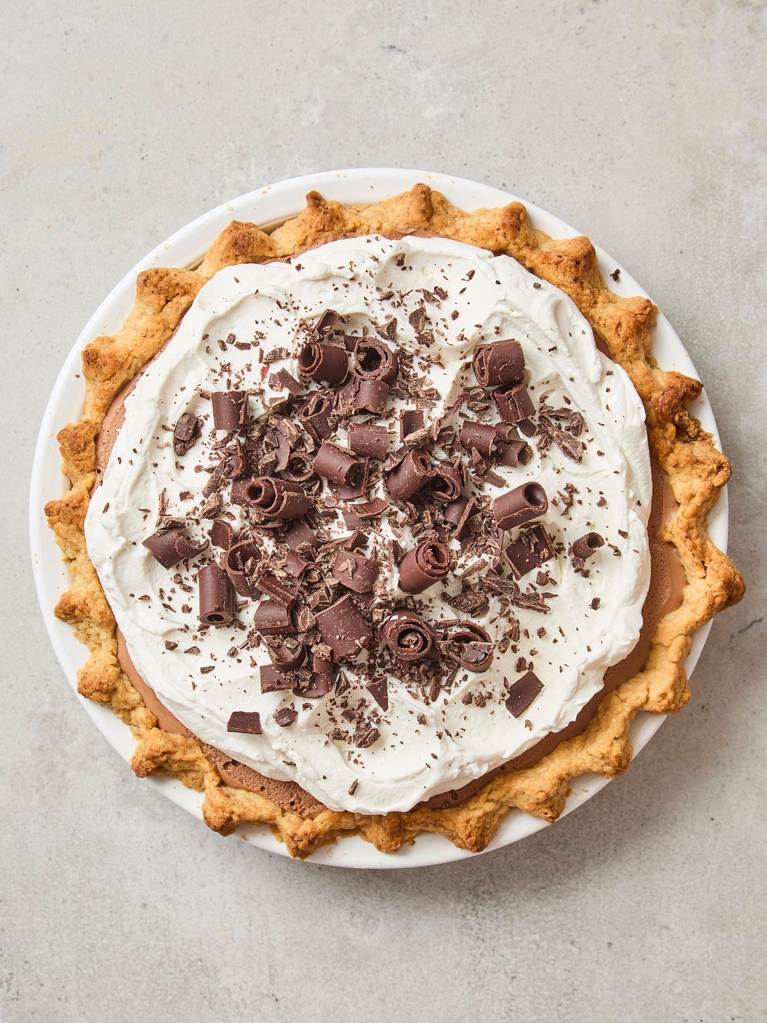 French silk pie with whipped cream and chocolate curls on top.