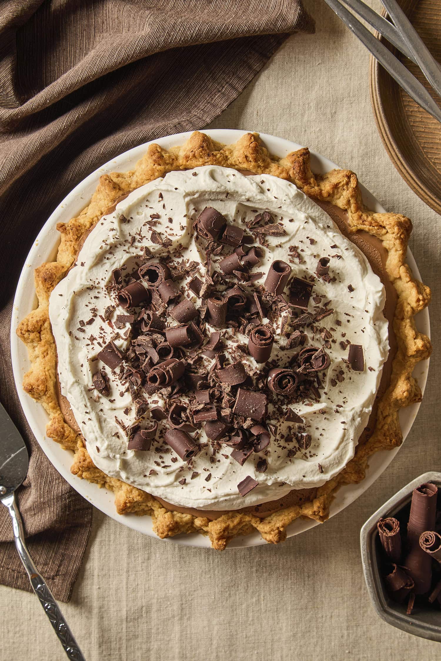 Full chocolate pie topped with whipped cream and chocolate curls before being sliced.