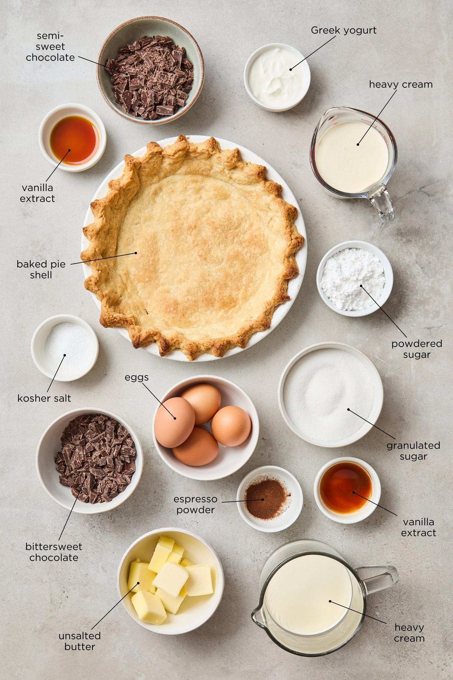 Concrete surface with ingredients for a French silk pie with a baked pie crust, chocolate, eggs, sugar, and more.