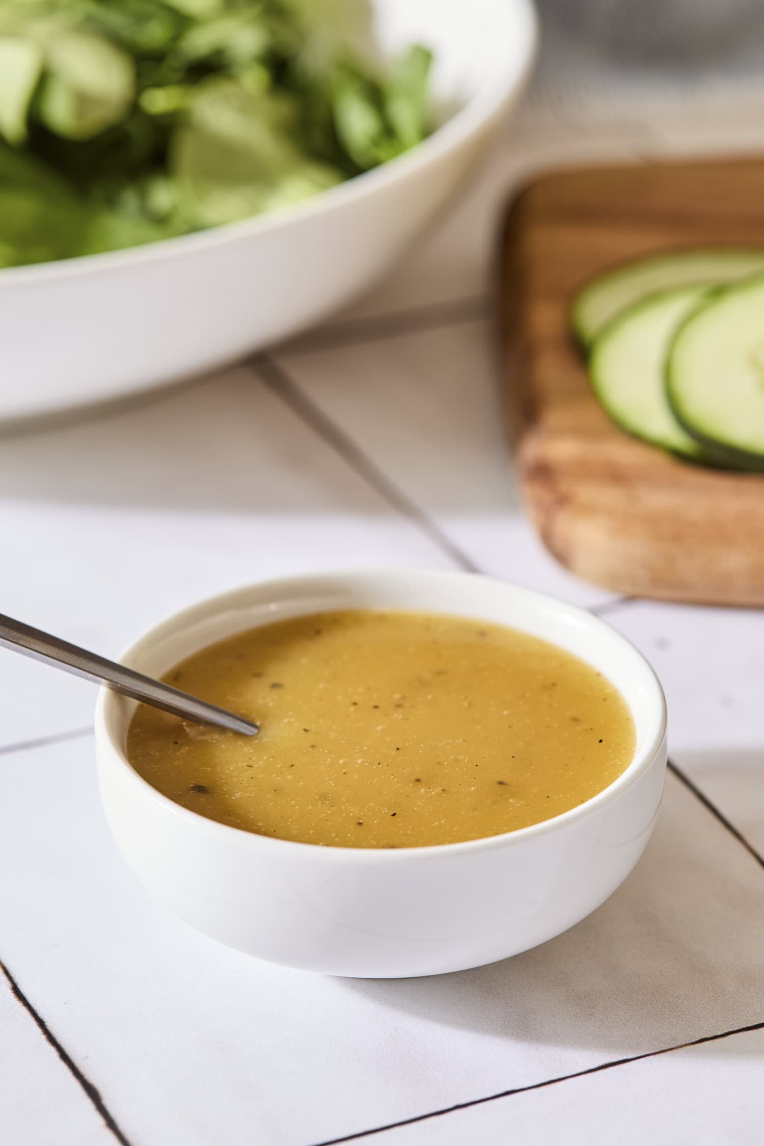 White bowl on a tile countertop with a golden vinaigrette inside.
