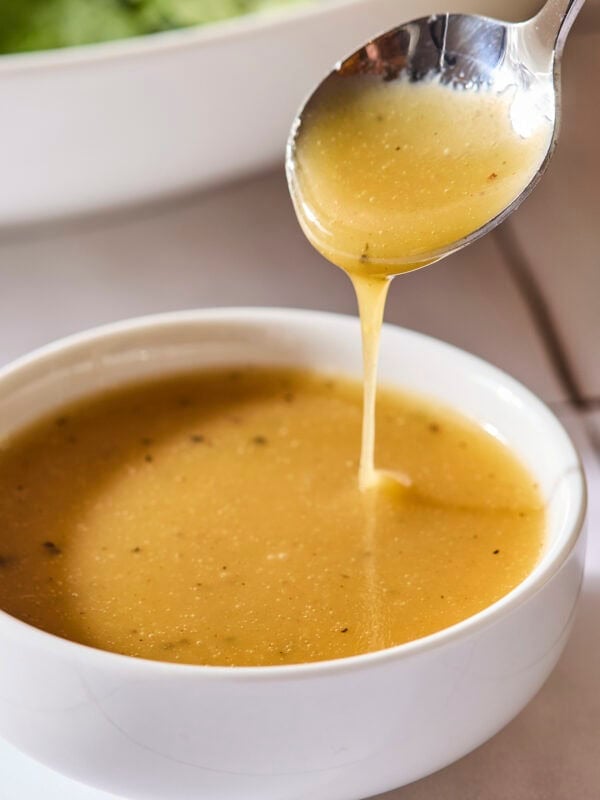 Honey Dijon vinaigrette with a spoon drizzling some into a bowl.