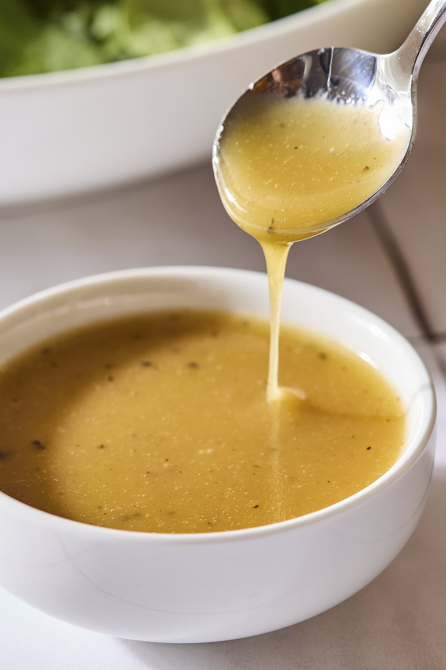 Honey Dijon vinaigrette with a spoon drizzling some into a bowl.