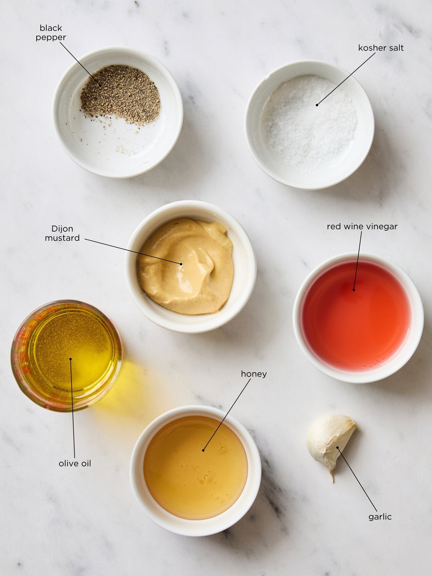 Marble surface with ingredients needed to make a vinaigrette.