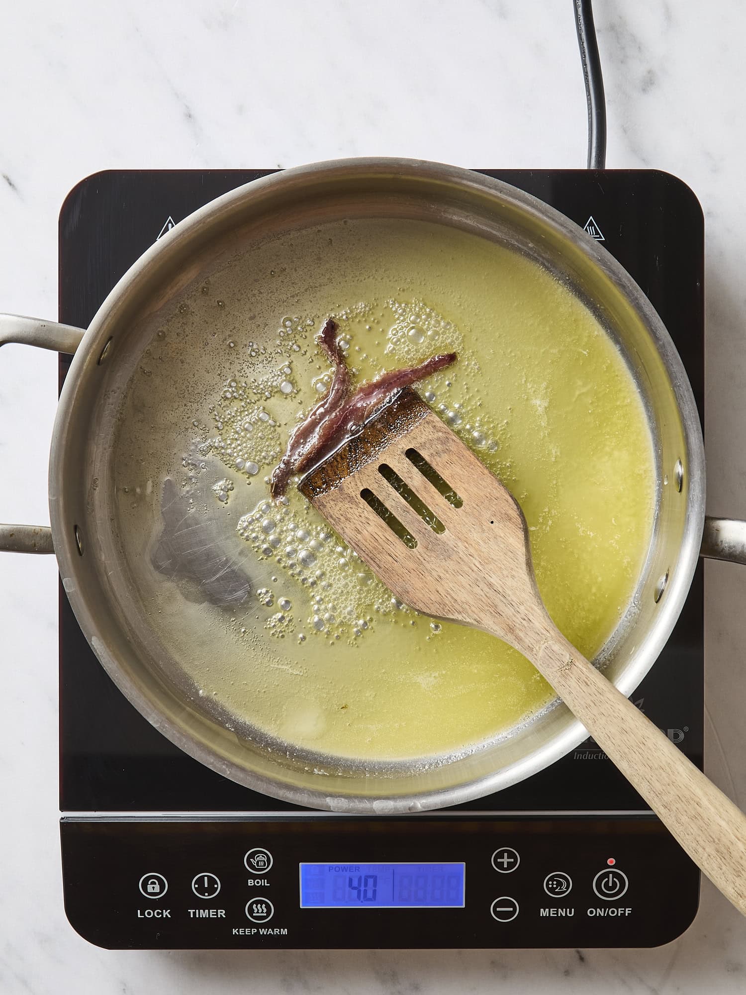 Butter and anchovies sautéing in a pan.