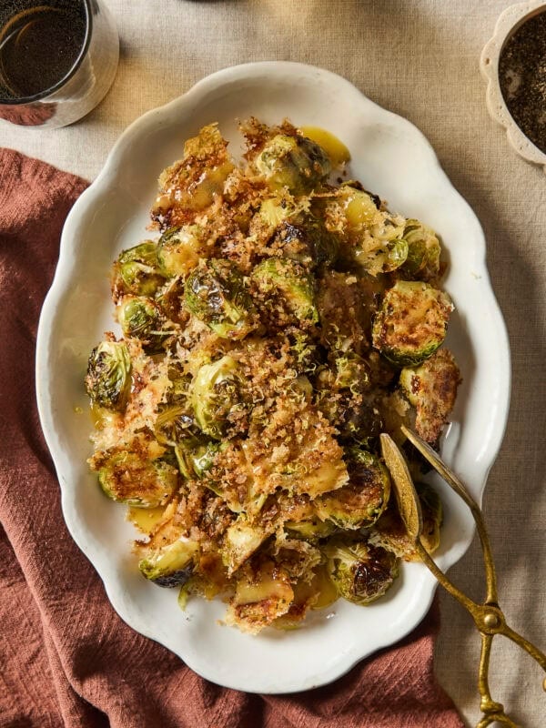 Decorative white platter filled with Parmesan roasted Brussels sprouts with crispy topping.