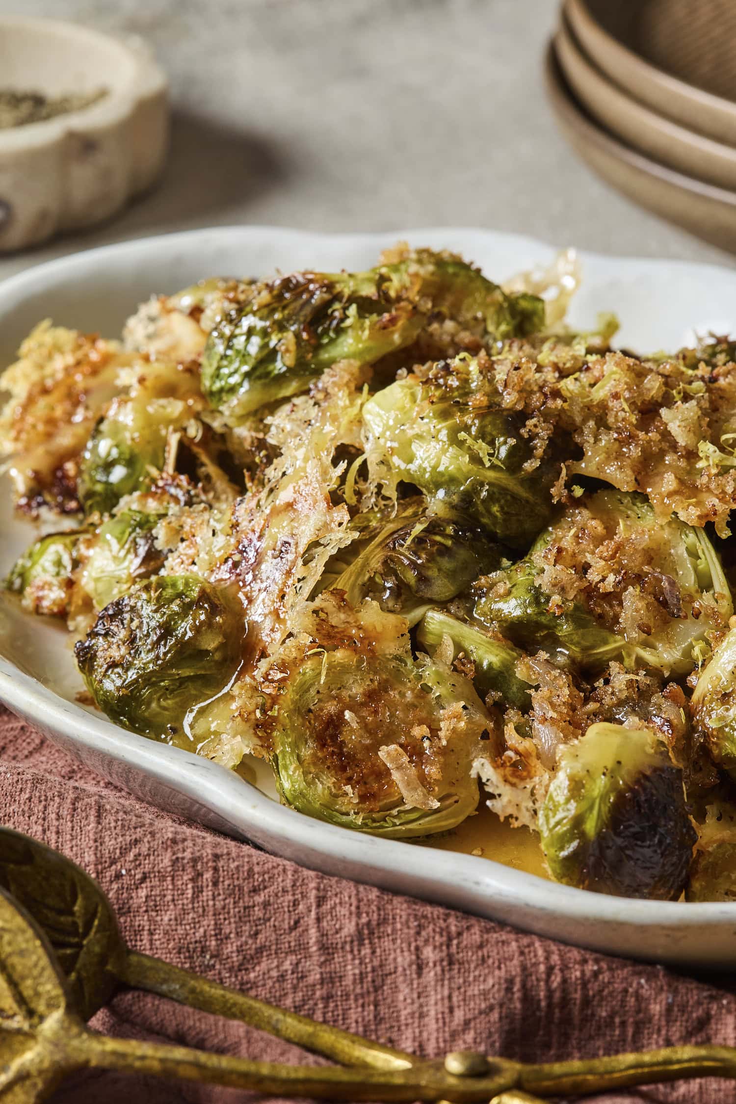 Crispy golden Brussels sprouts on a platter with dressing drizzled on top.