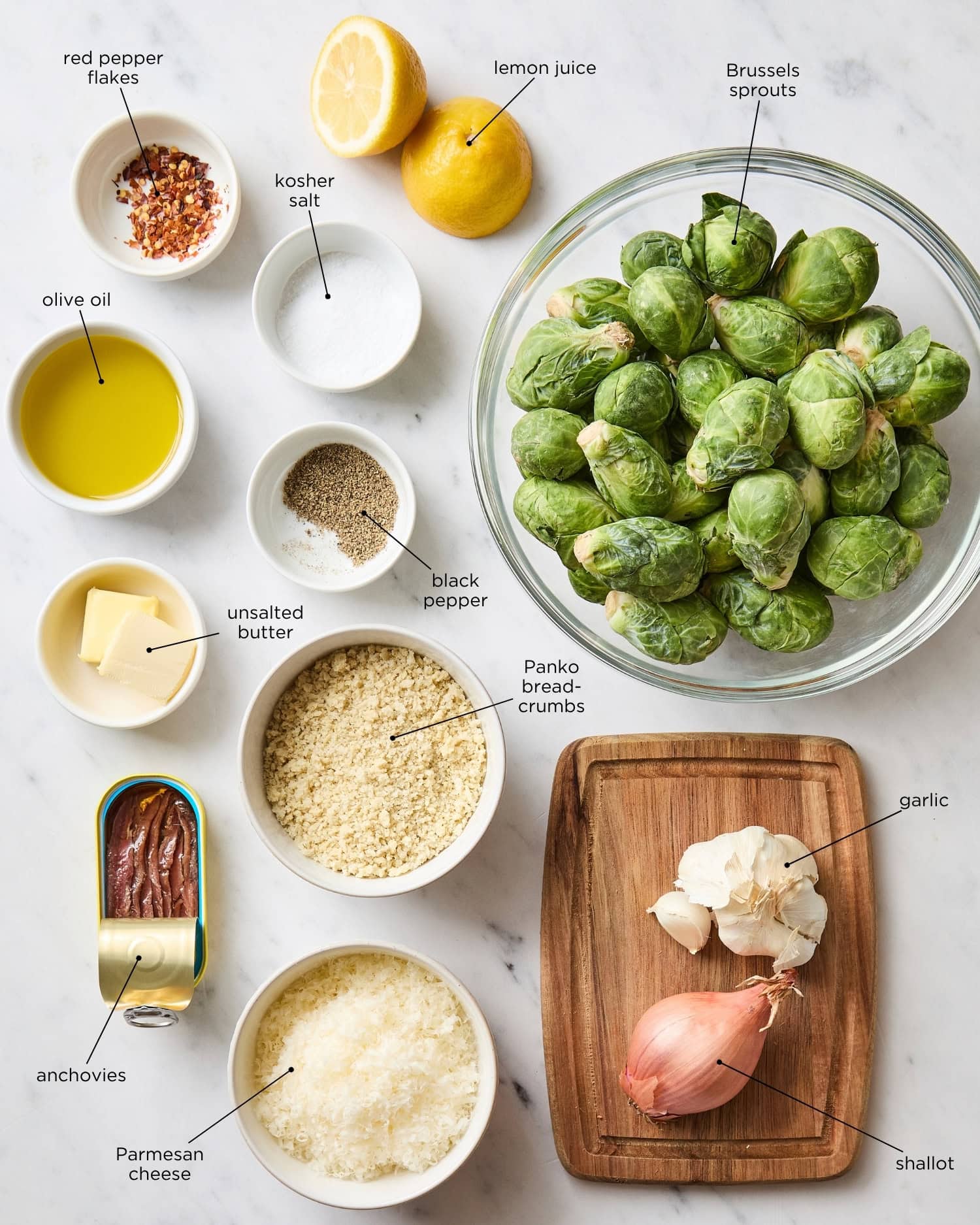 Marble surface with ingredients to make roasted Brussels sprouts with Parmesan topping.