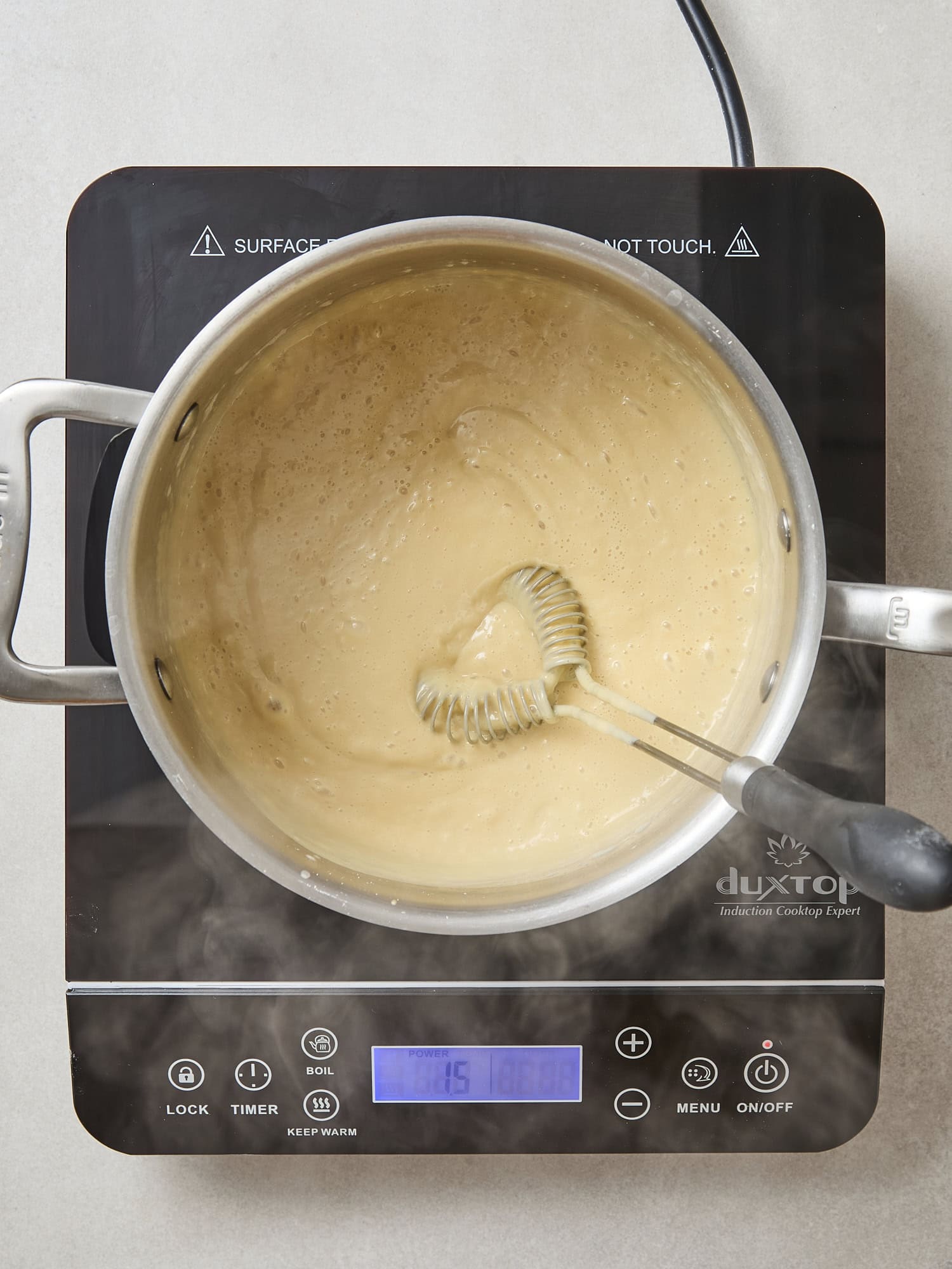 Pan with milk mixture on heat with steam.